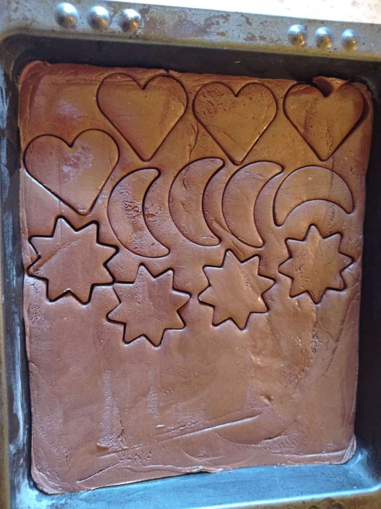 Close-up of set chocolate in a tray, pressed with cookie cutters to form shapes