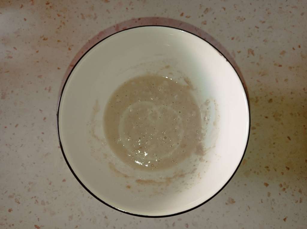 Small bowl with a mixture of yeast, sugar, a tablespoon of flour, and 50 ml of water for activating yeast.