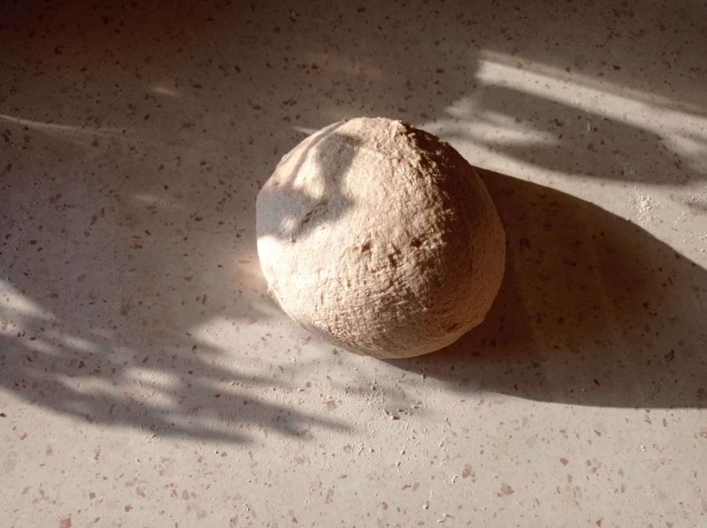 Smooth and elastic bread dough ball on a floured work surface