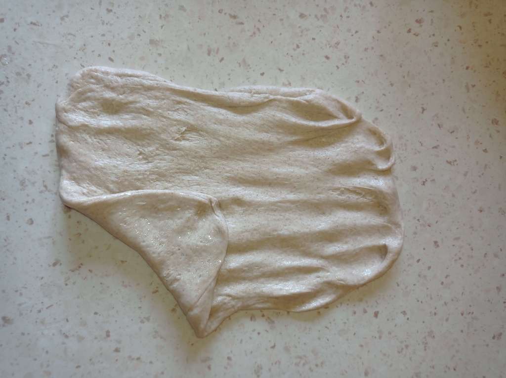 Bread dough undergoing second stretch and fold on oiled work surface