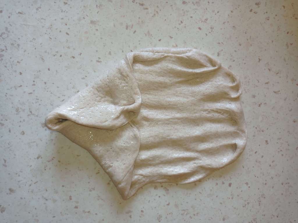 Bread dough undergoing second stretch and fold on oiled work surface