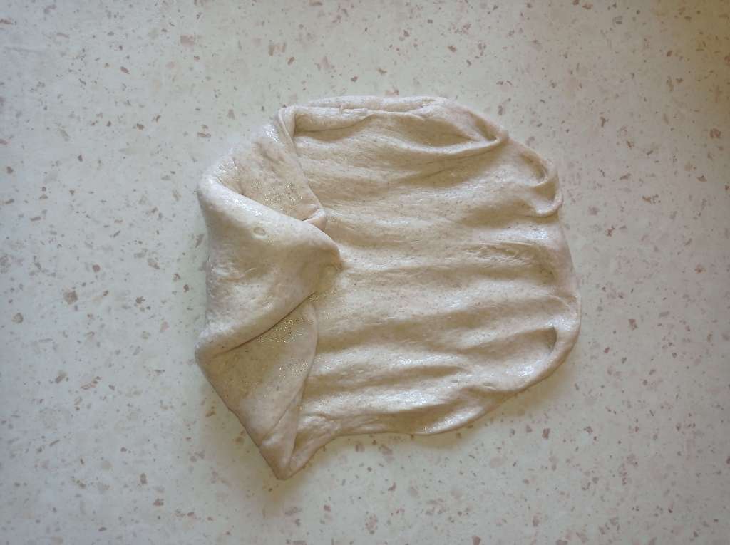 Bread dough undergoing second stretch and fold on oiled work surface