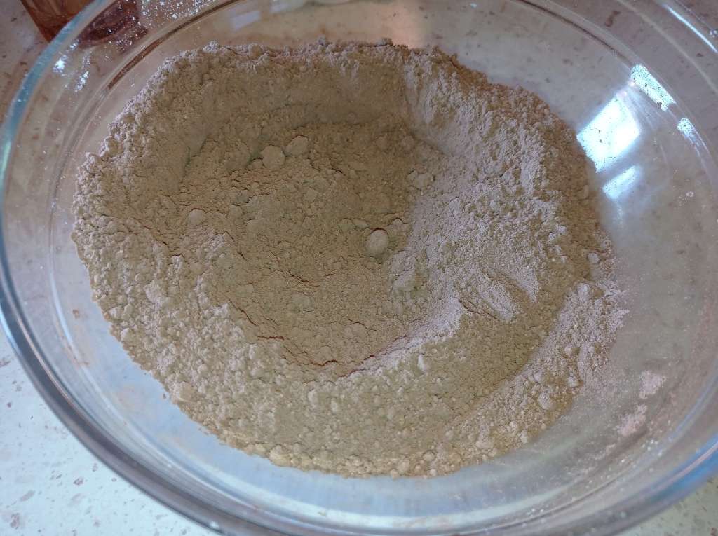Close-up of sifted cocoa and milk powder fully mixed together in a glass bowl
