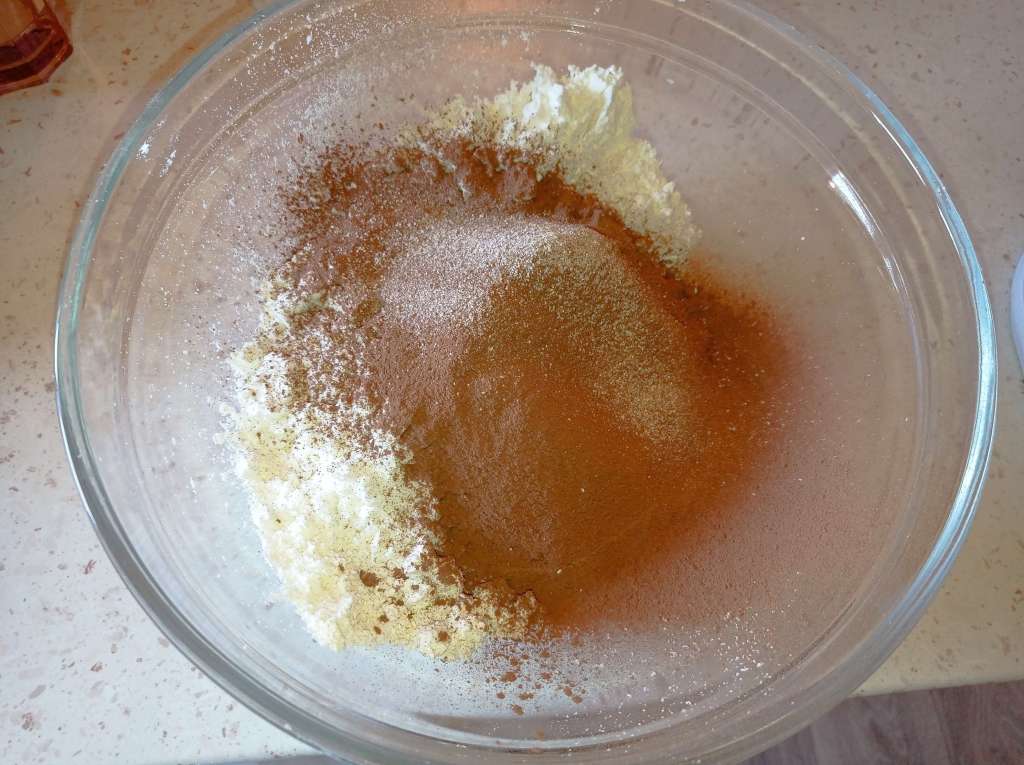 Close-up of sifted cocoa powder added to sifted milk powder in a glass bowl, ready for mixing