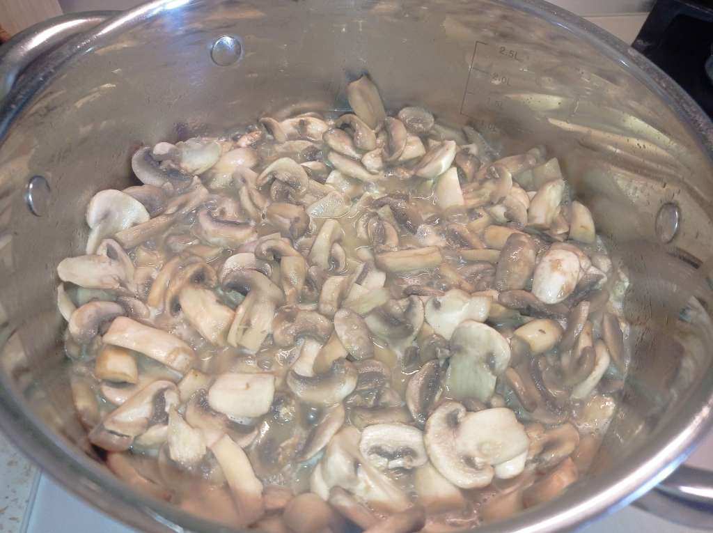 Stewed mushrooms in a stainless steel pot on a gas stove, cooked until tender