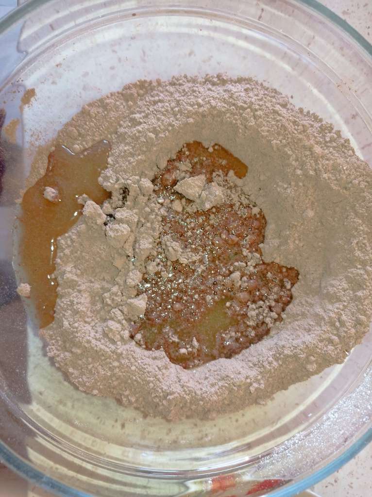 Close-up of chocolate syrup being poured over a milk powder and cocoa mixture in a large bowl