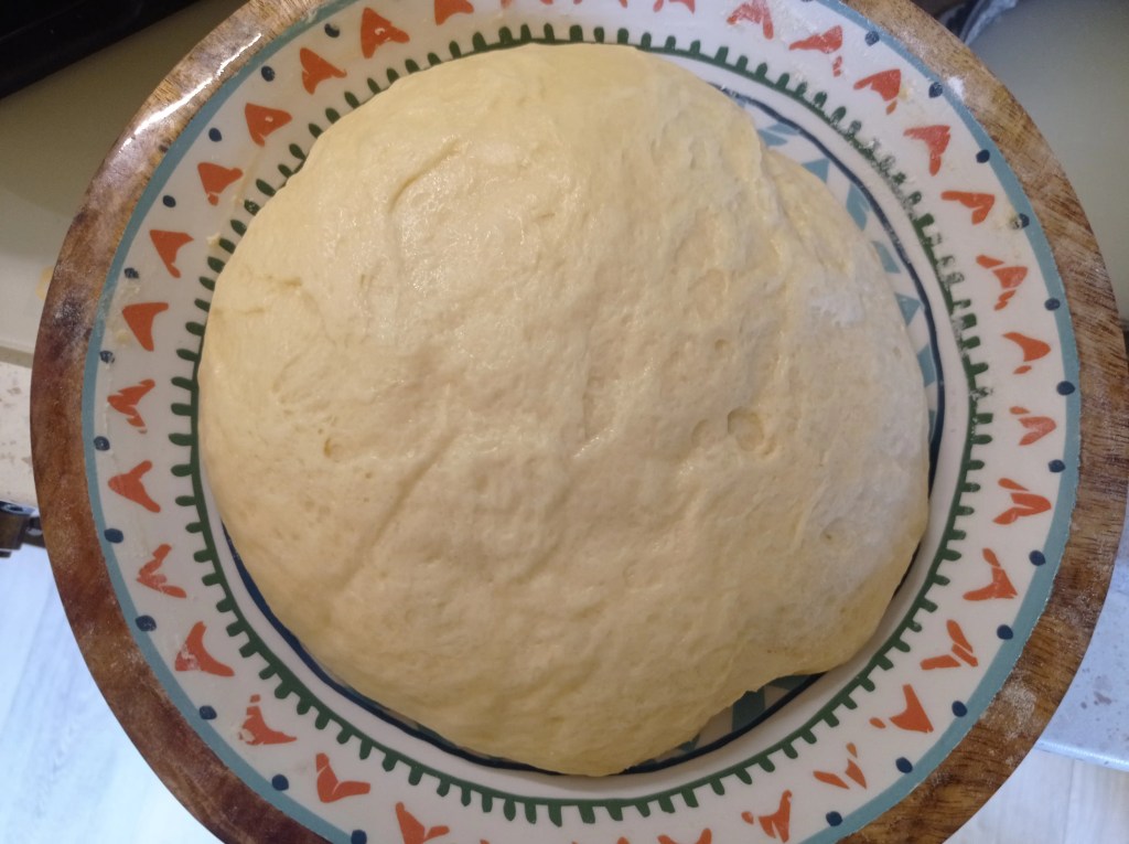 Fluffy risen dough for traditional Romanian Pasca resting in a glass bowl after two hours