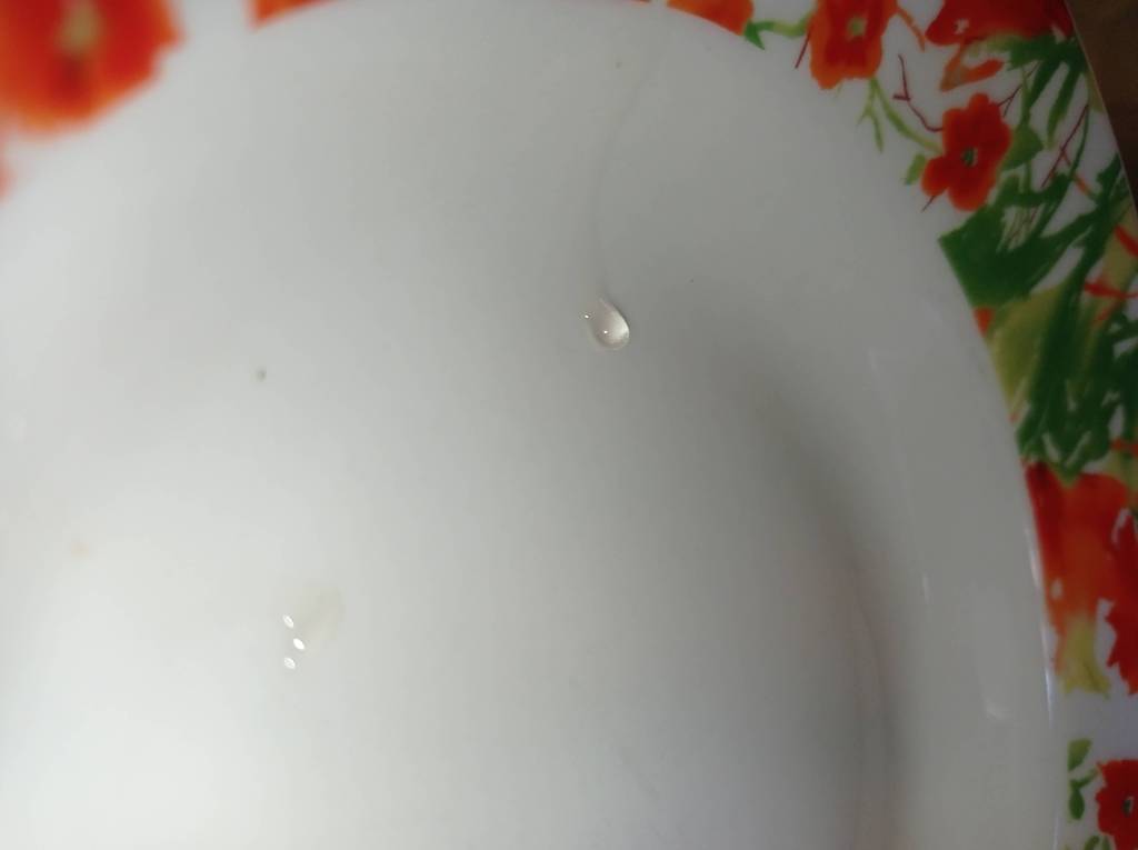 A drop of sugar syrup forming a thin thread on a plate to check consistency.