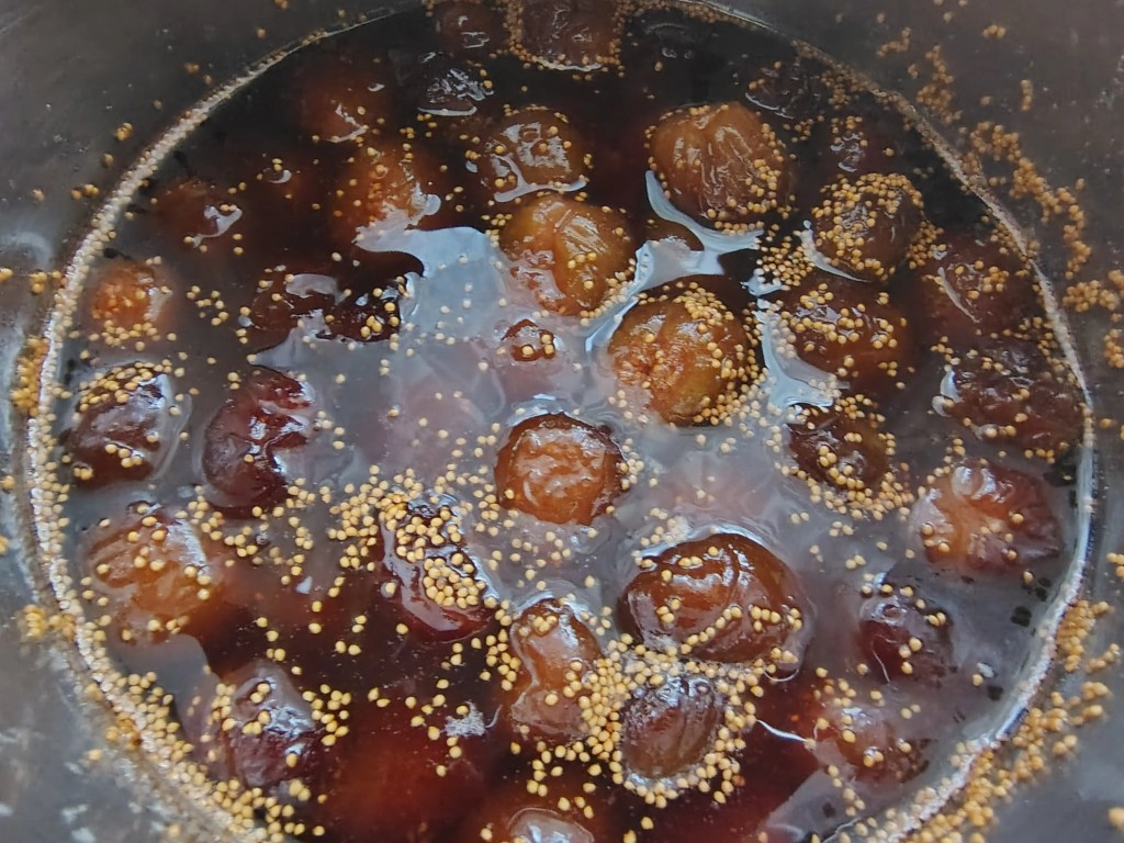 Traditional fig jam fully cooled, showing whole figs suspended in a rich, glossy syrup.