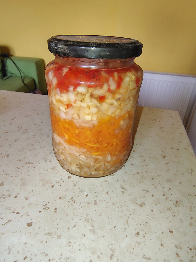 Layered vegetable mix in a jar for winter soups, with grated and chopped root vegetables, carrots, celery, and tomatoes, preserved Romanian-style.