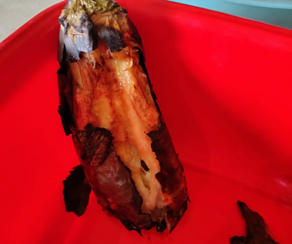 Close-up of a roasted eggplant with the skin partially peeled off, showing the soft cooked flesh inside