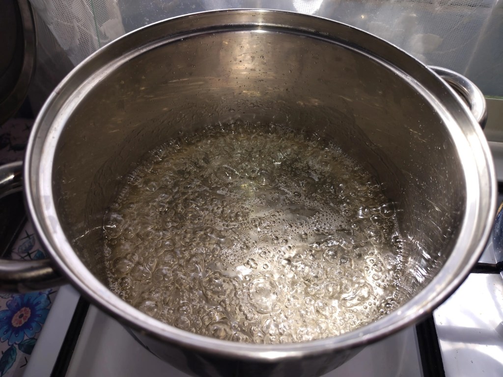 Sugar syrup boiling in a stainless steel pot, showing the correct consistency for fig jam.