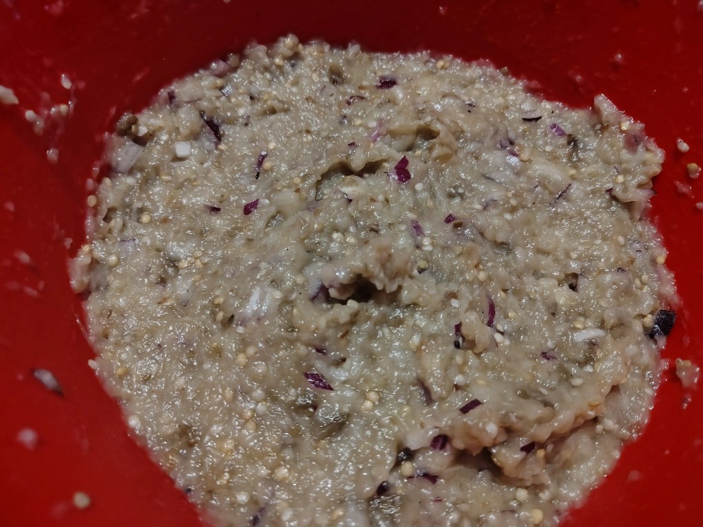 creamy Romanian eggplant salad with red onion mixed in a red bowl