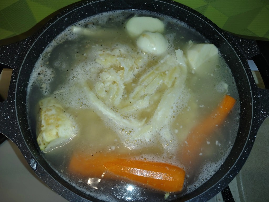 Beef tripe and whole vegetables simmering in a pot of broth for traditional Romanian tripe soup.